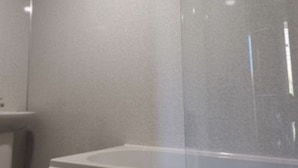 Un baño con paredes y bañera blancos.