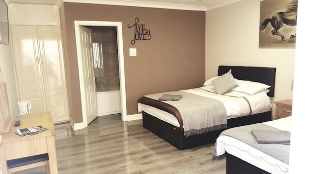 Un dormitorio con cama, mesitas de noche, armario y puerta que da a un baño.