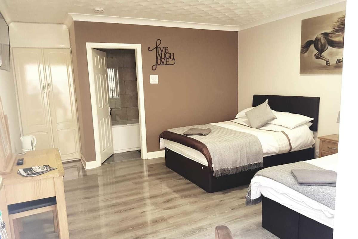 Um quarto com cama, mesas de cabeceira, guarda-roupa e uma porta que dá para o banheiro.