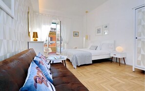 A modern bedroom with a bed, a sofa, a bedside table, and a lamp.