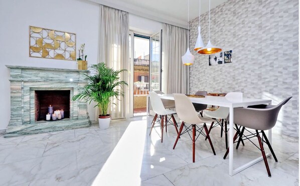 A modern dining area with a marble fireplace, white dining table, and chairs.