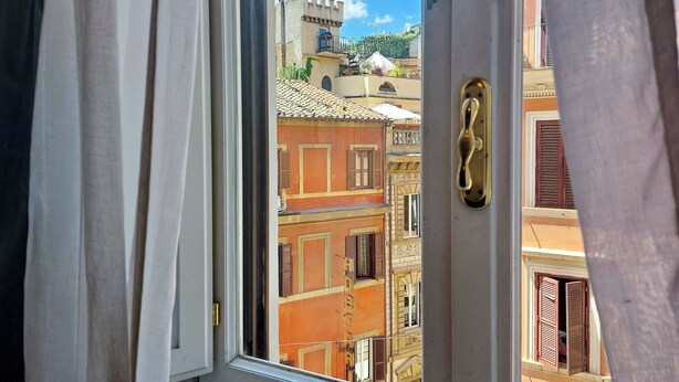 Une vue à travers une fenêtre avec une porte, dévoilant un bâtiment doté de balcons et d’une tour.