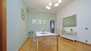 Un espace repas comprenant une table blanche, des chaises transparentes et une console blanche agrémentée d’un miroir et d’objets décoratifs.