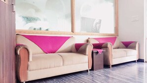 A room with two beige sofas, a small table, and a large window with a view of a building.