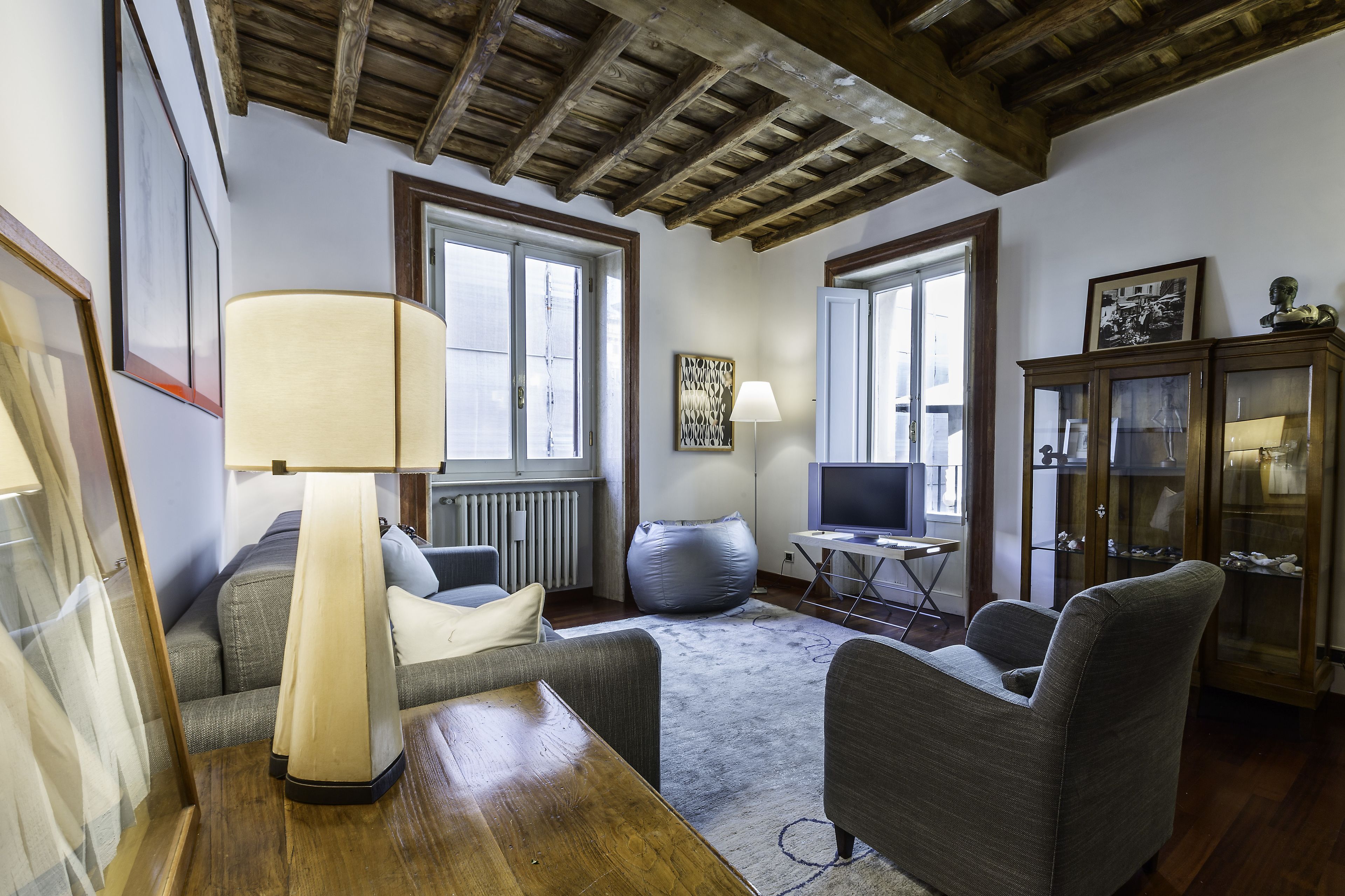 A living room with a wooden ceiling, a sofa, a table, a lamp, and a cabinet.
