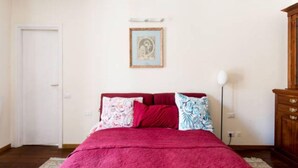 A bedroom with a bed, a framed picture on the wall, a bedside lamp, and a wooden dresser. - Superbe penthouse to Piazza Navona (Rome)