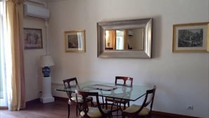 A dining area with a glass table and wooden chairs, a large mirror on the wall, and framed pictures. - Superbe penthouse to Piazza Navona (Rome)