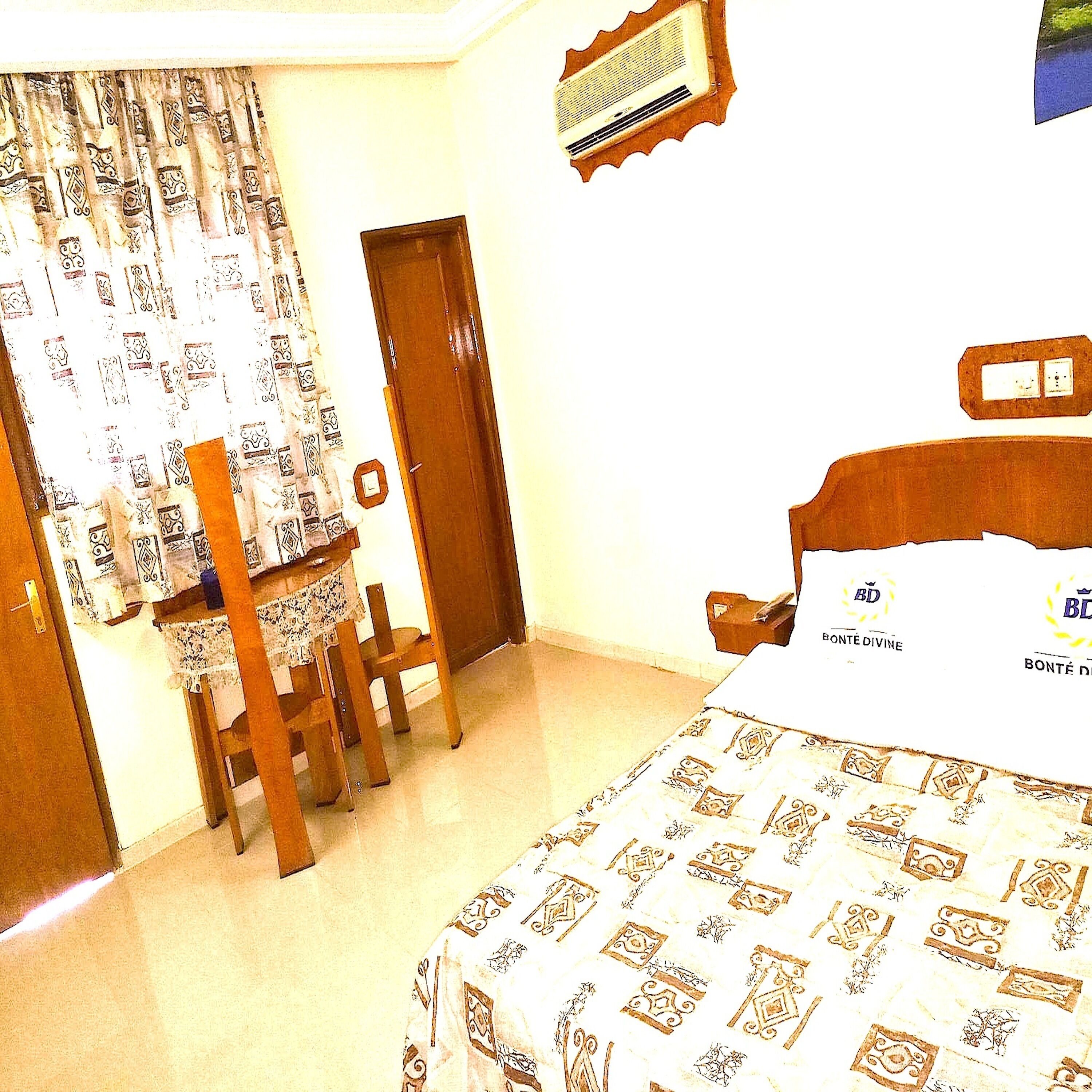 Une chambre à coucher comprenant un lit, une chaise, un bureau et un appareil de climatisation.