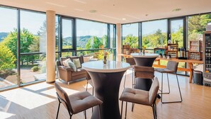 Una habitación amplia con ventanas grandes, una mesa redonda y muebles modernos.