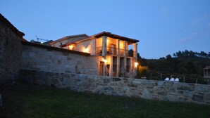 A stone building with a balcony and a stone wall in front. - Alojamiento Rural Pazos (San Cristovo de Cea)