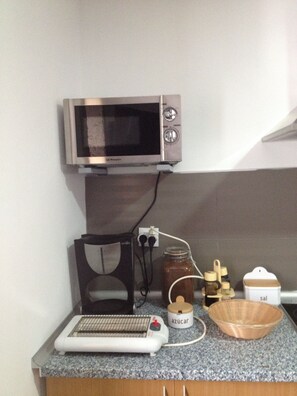 A kitchen with a microwave, a coffee maker, a jar labeled 'azucar', and a wooden bowl on the counter. - Alojamiento Rural Pazos (San Cristovo de Cea)