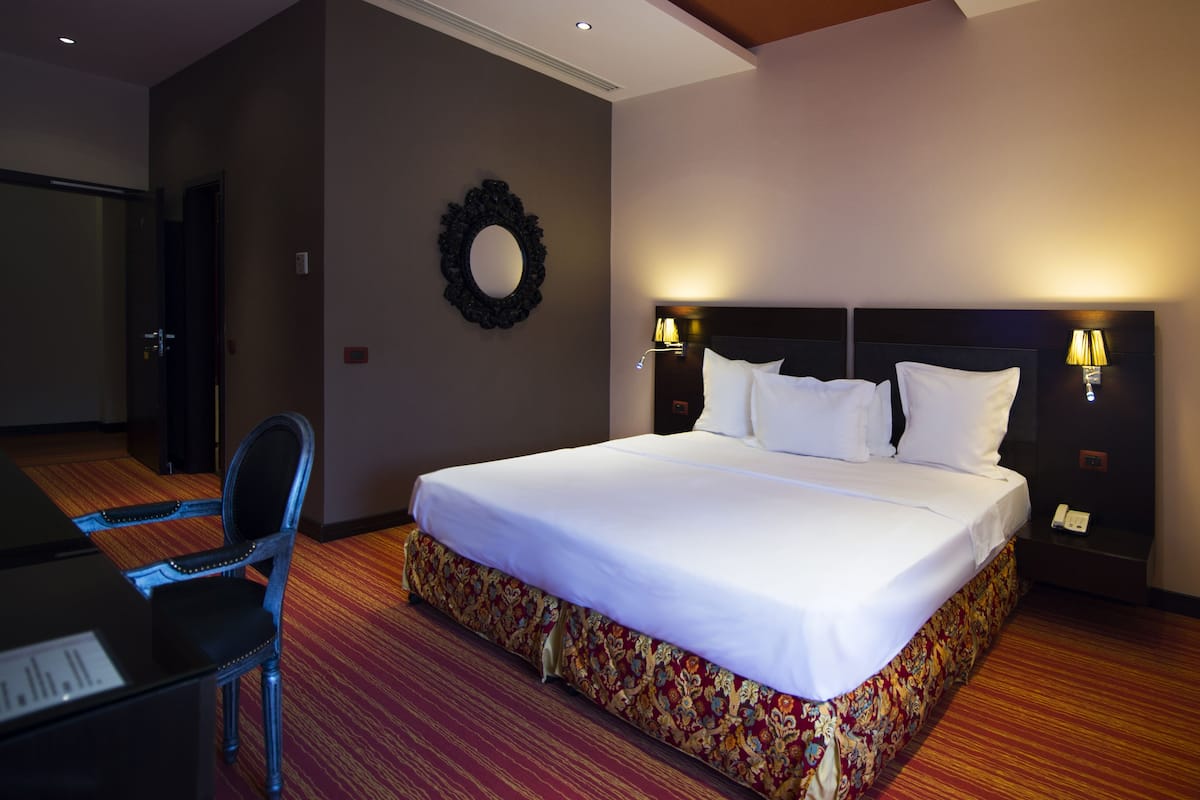 A hotel room with a large bed, a desk, and a chair.