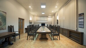 A conference room with a long table, chairs, a wooden floor, a television, and a large window with blinds. - Nane Hotel (Gyumri)