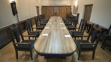 Un salón de conferencias con una larga mesa de madera, sillas negras y un fondo de madera.