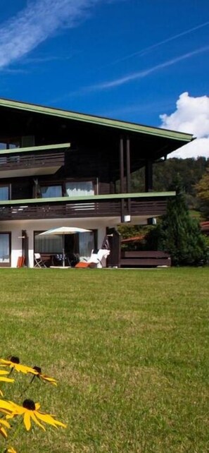 A two-story building with a flat roof and a covered patio area.