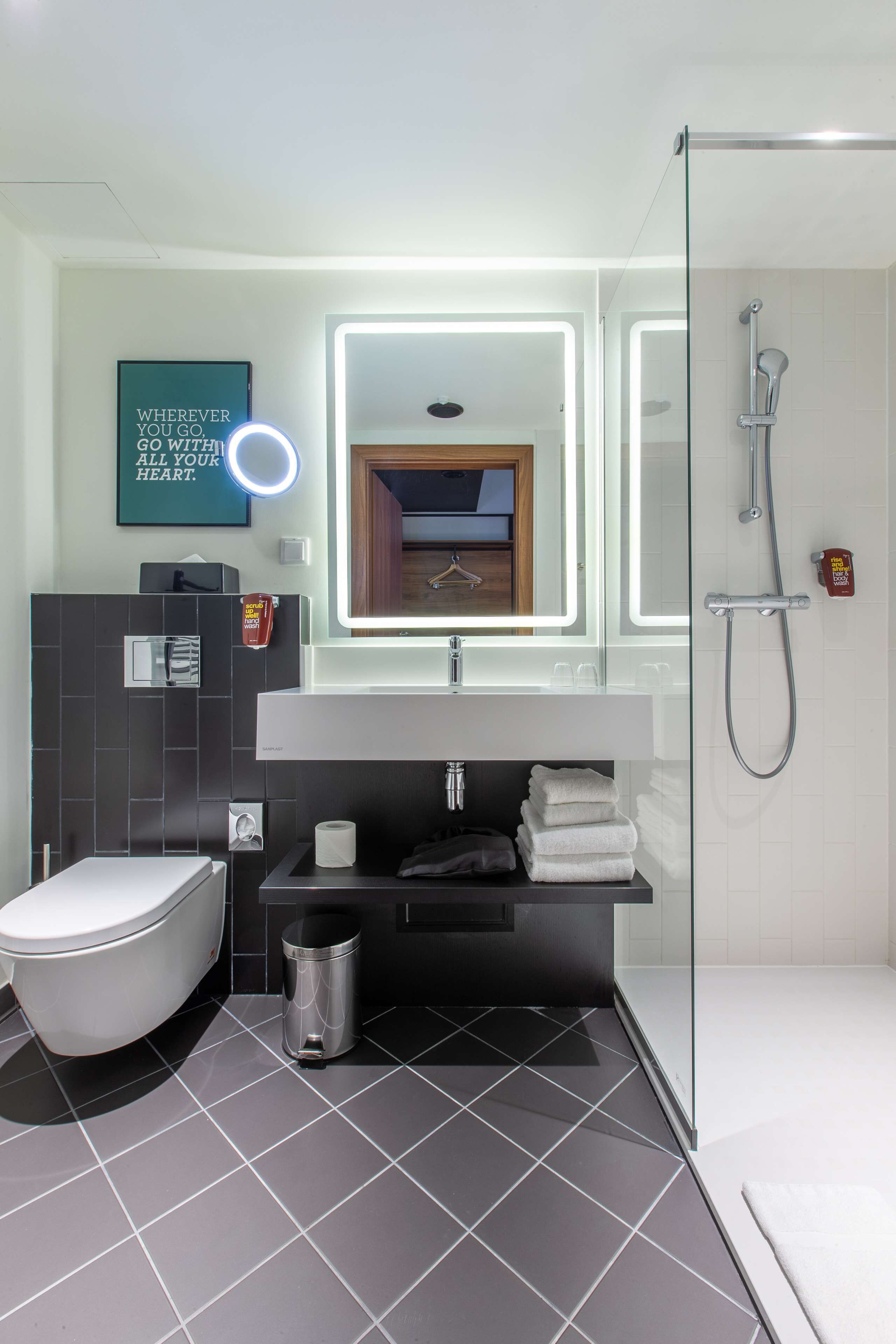 Een moderne badkamer met toilet, wastafel en douche.
