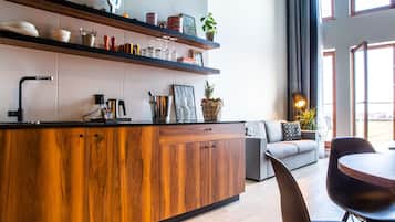 Una cocina moderna con armarios de madera, encimera negra y estante empotrado con diversos utensilios de cocina.