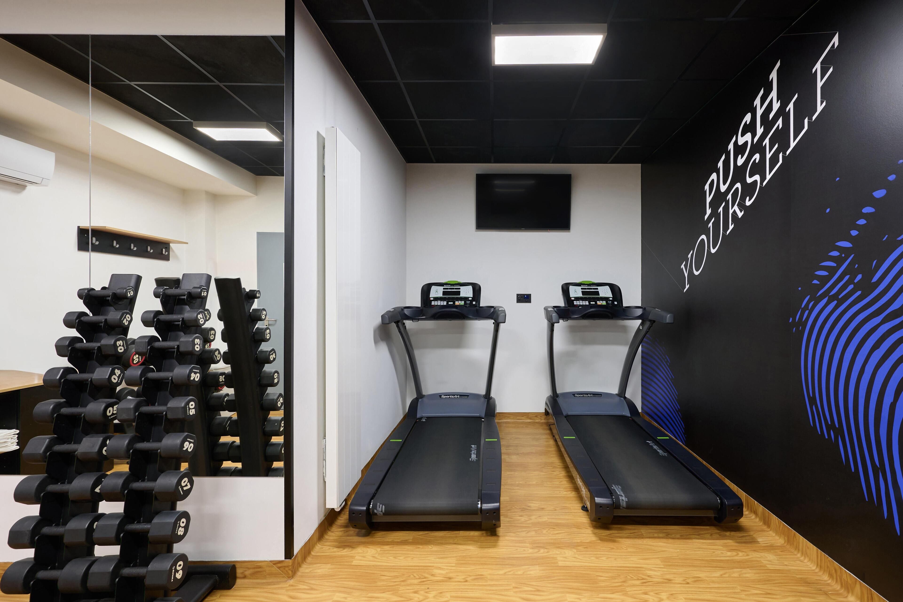 A gym with treadmills, dumbbells, and a motivational wall.