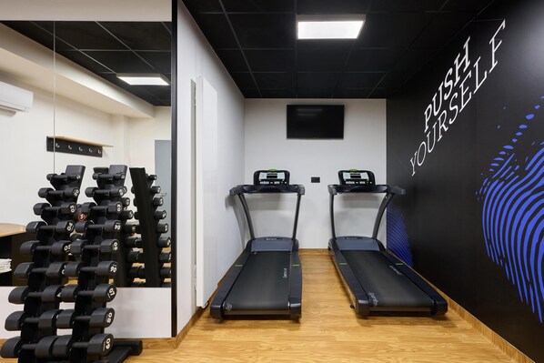 A gym with treadmills, dumbbells, and a motivational wall.