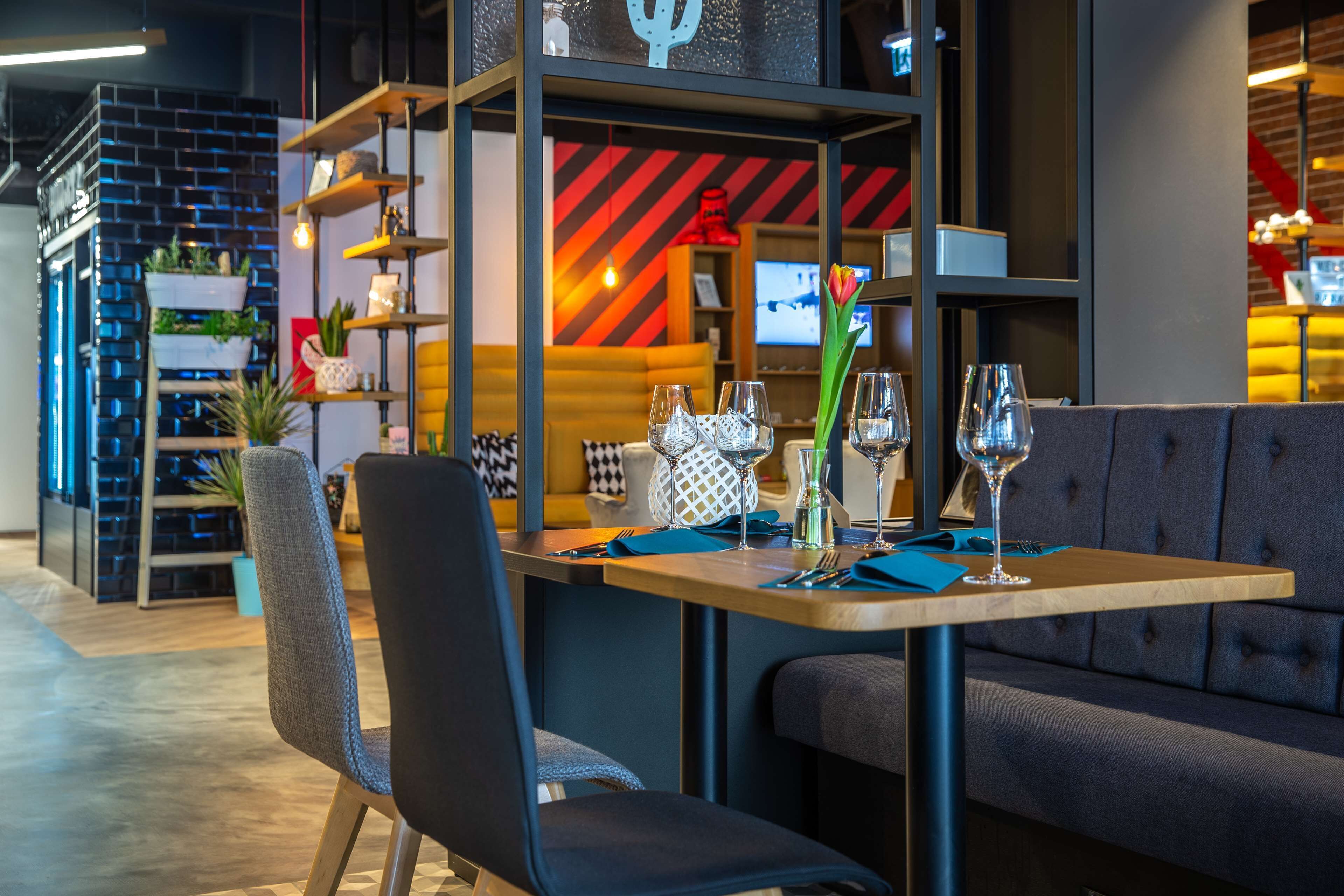 A modern restaurant with a booth seating arrangement, a bar area with shelves, and a television in the background.