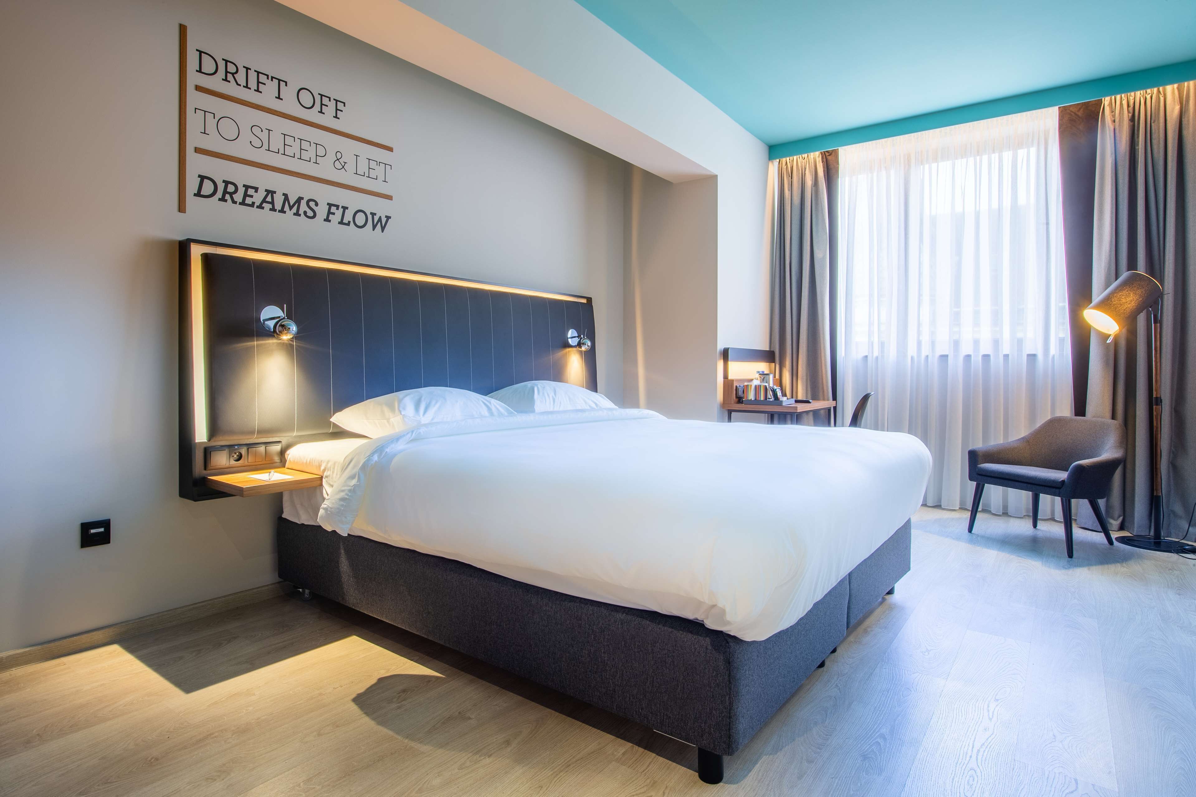 Una habitación de hotel moderna con una cama grande, mesitas de noche, un escritorio y una silla.