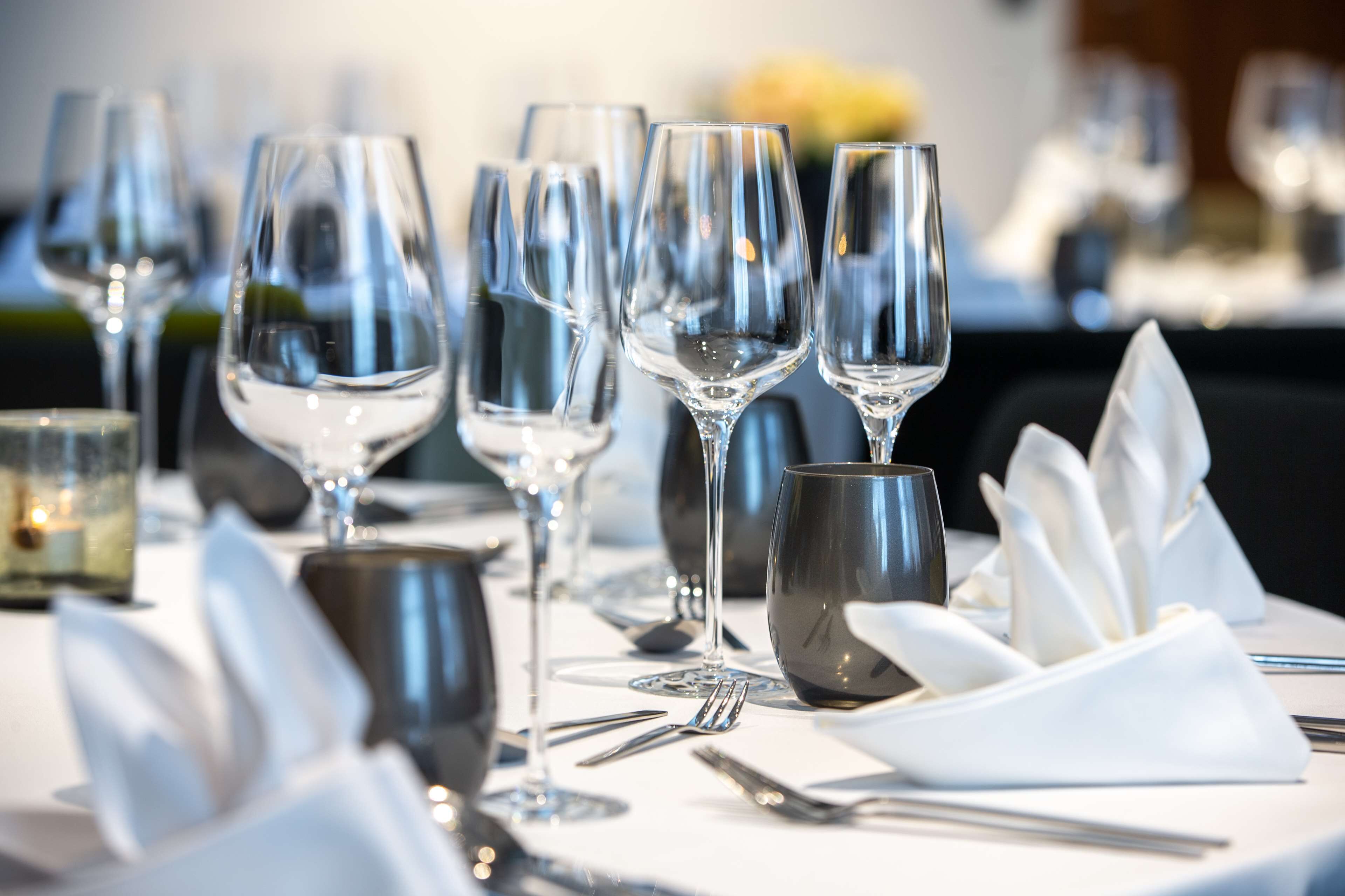 Une table à manger dressée avec plusieurs verres à vin, un saladier et des couverts.