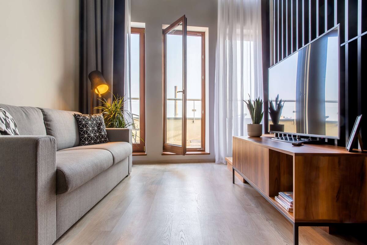 A modern living room with a sofa, a TV, and a wooden cabinet.