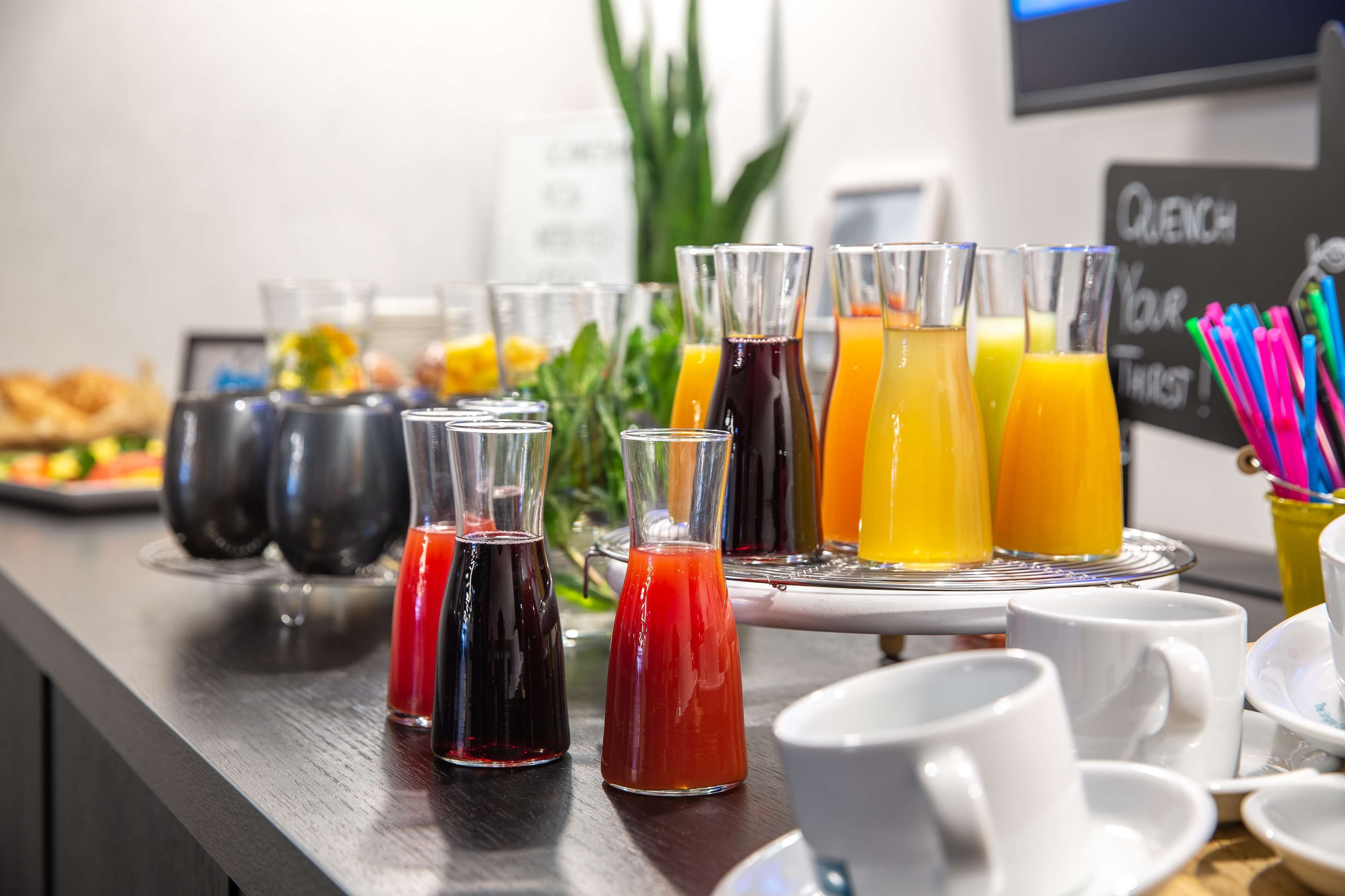 Un buffet per la colazione con diversi succhi e un cartello con la scritta "QUENCH YOUR THIRST".