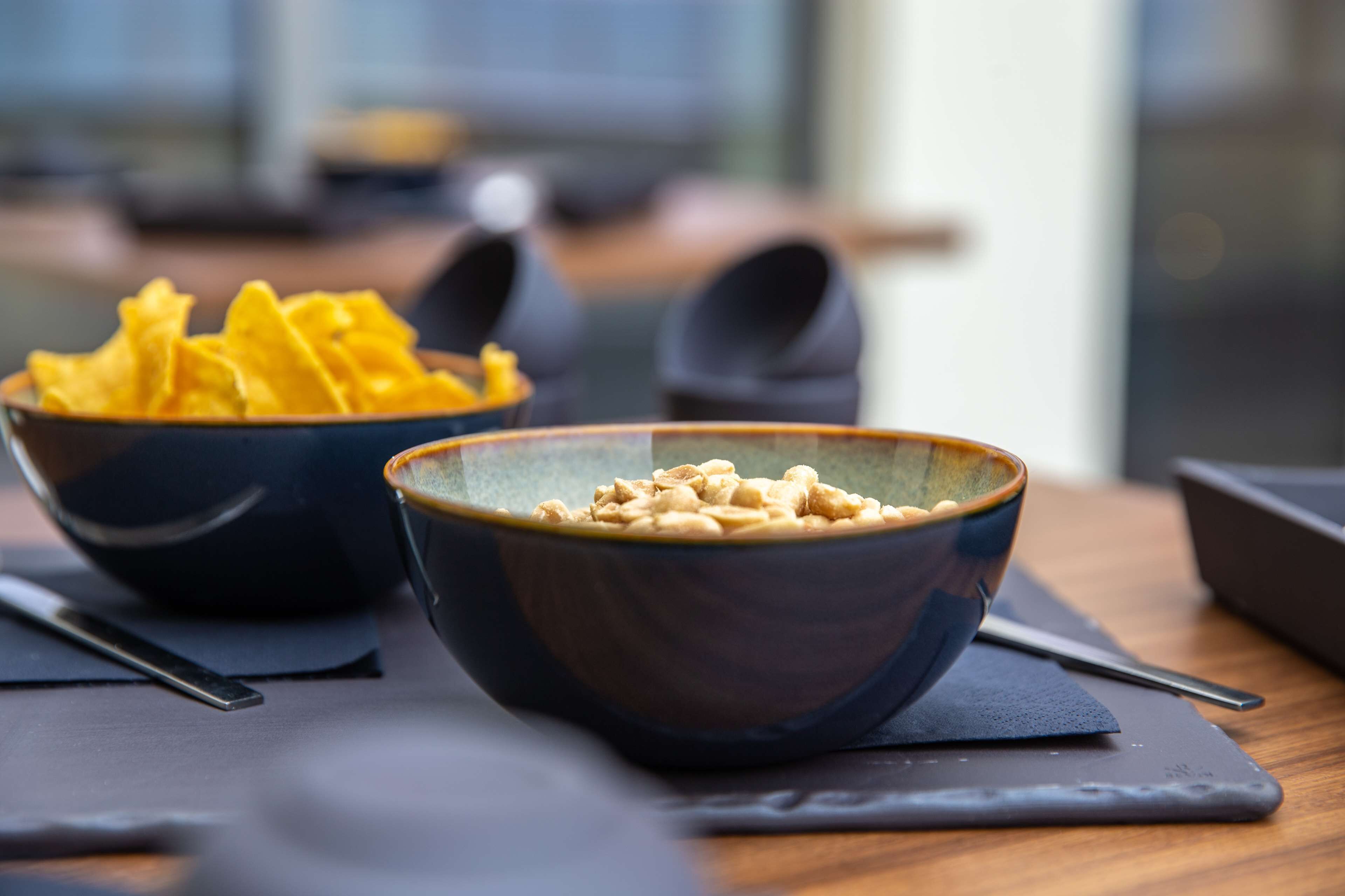 Two bowls of food on a table with a napkin and a spoon.