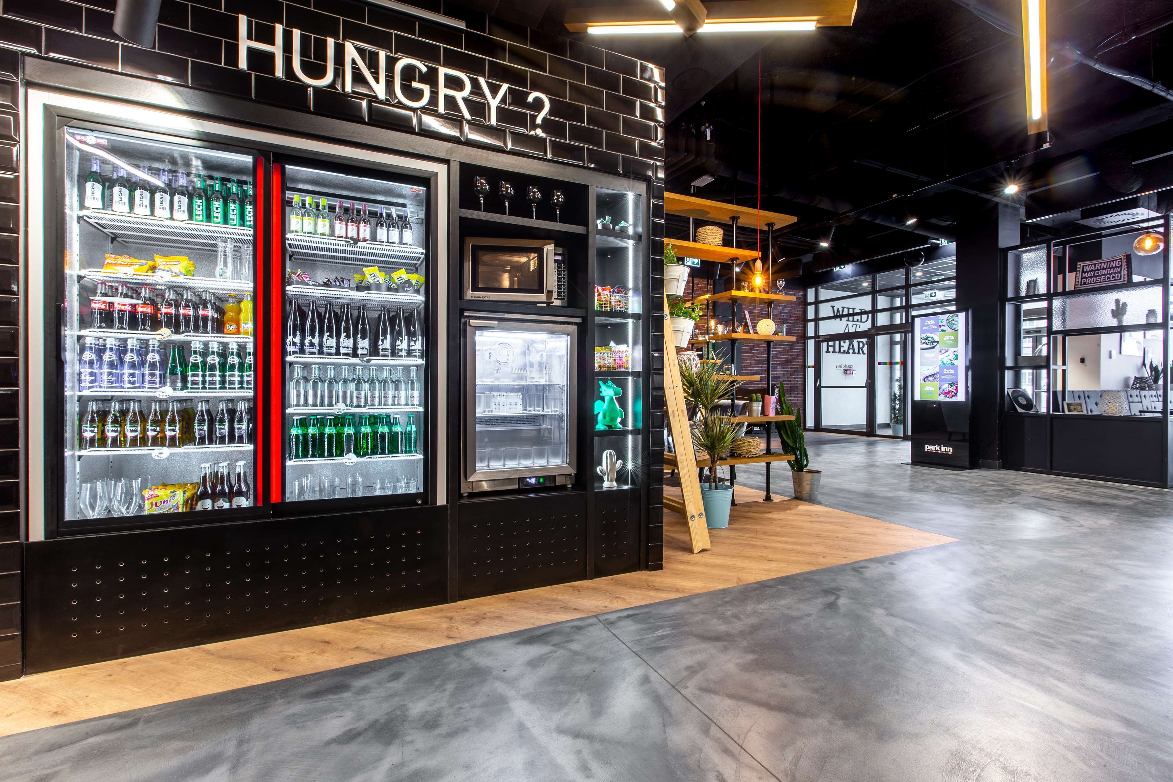 Un moderno puesto de bebidas con una decoración en blanco y negro, que cuenta con varios dispensadores y estantes llenos de aperitivos.