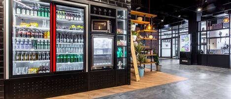 Un moderno puesto de bebidas con una decoración en blanco y negro, que cuenta con varios dispensadores y estantes llenos de aperitivos.