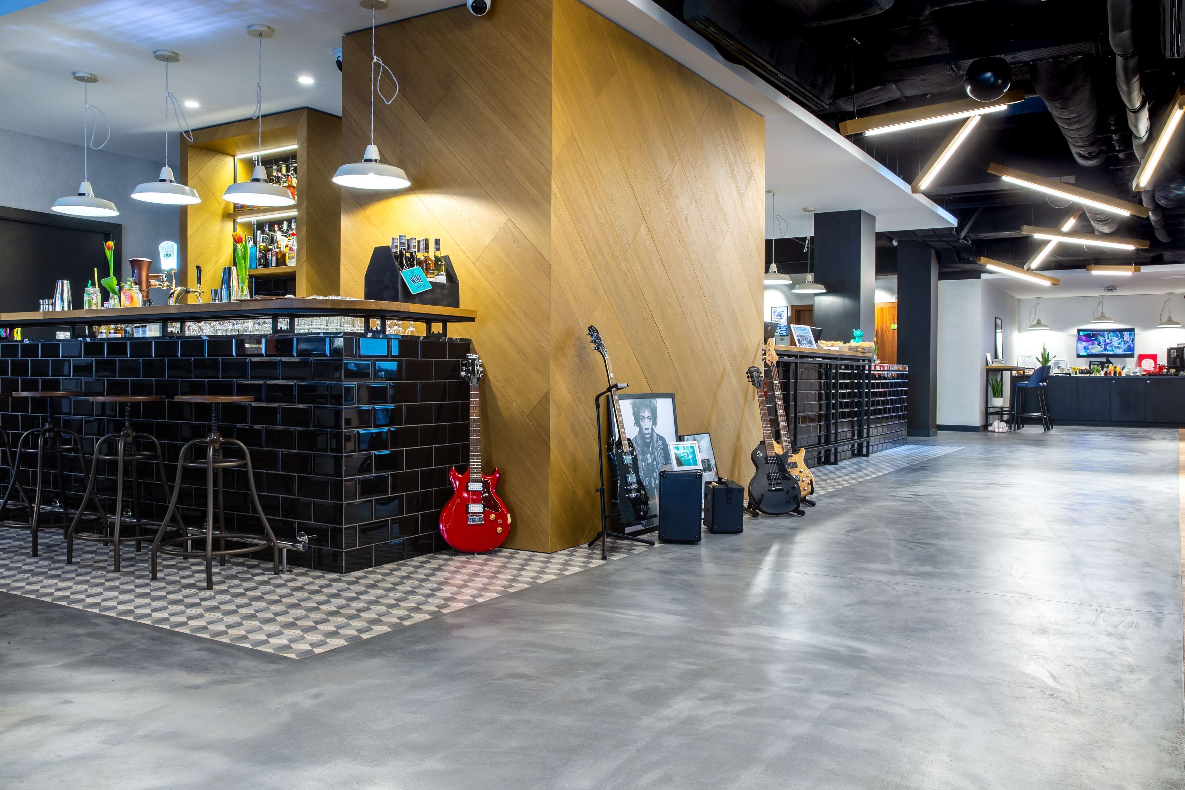 A modern bar area with a wooden accent wall, bar stools, and guitars.