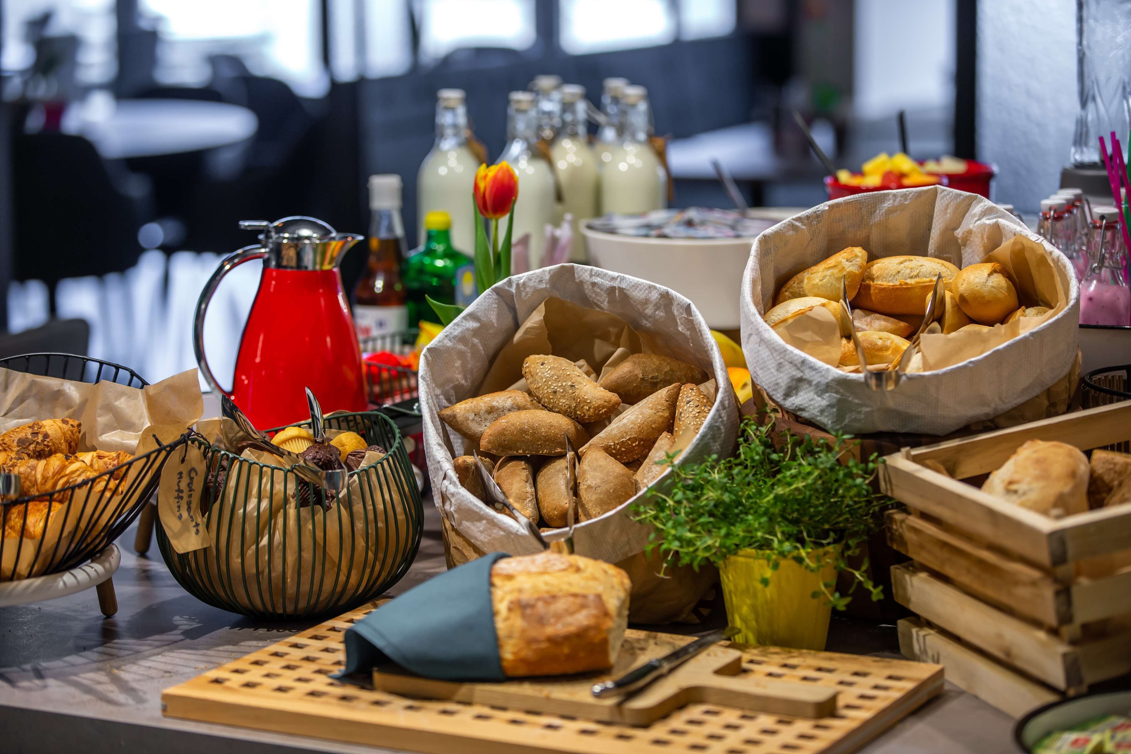 A buffet table with various food items, including bread, pastries, and condiments.