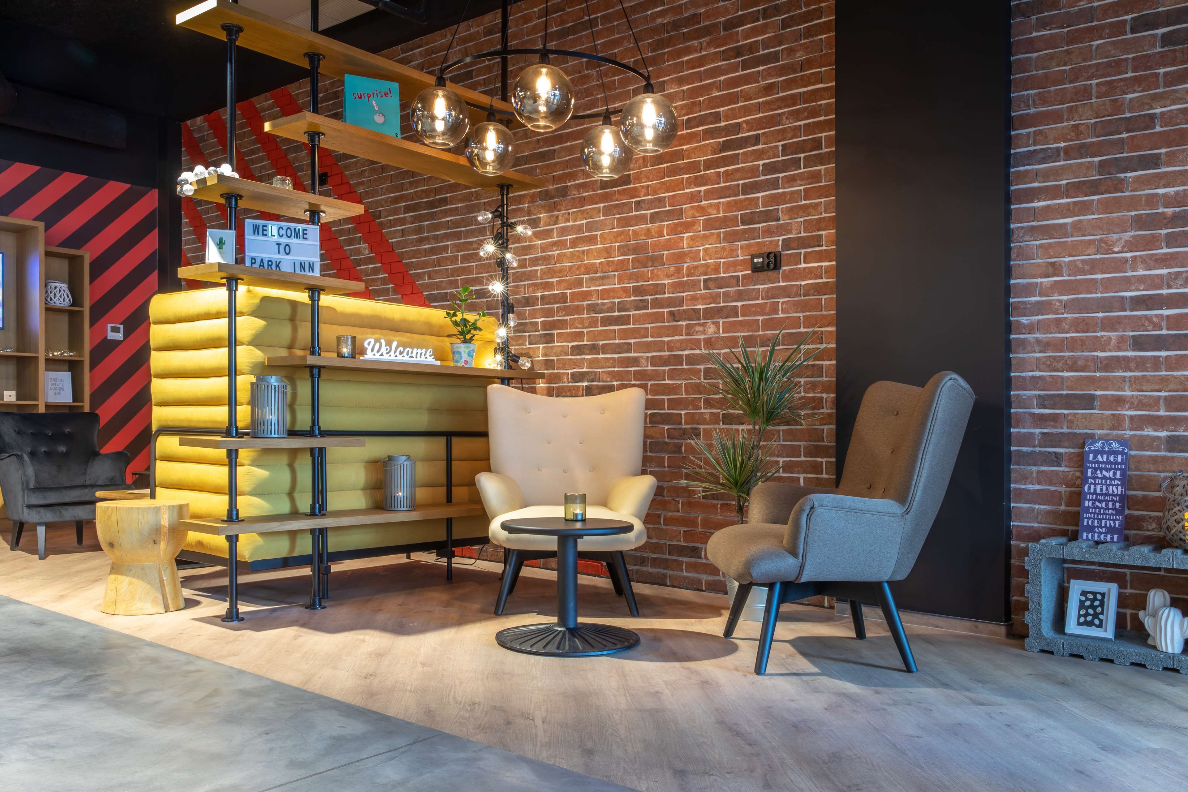Een gezellige zithoek met een gele bank, twee fauteuils en een kleine ronde tafel. Een bordje luidt: 'Welcome to Park Inn'.