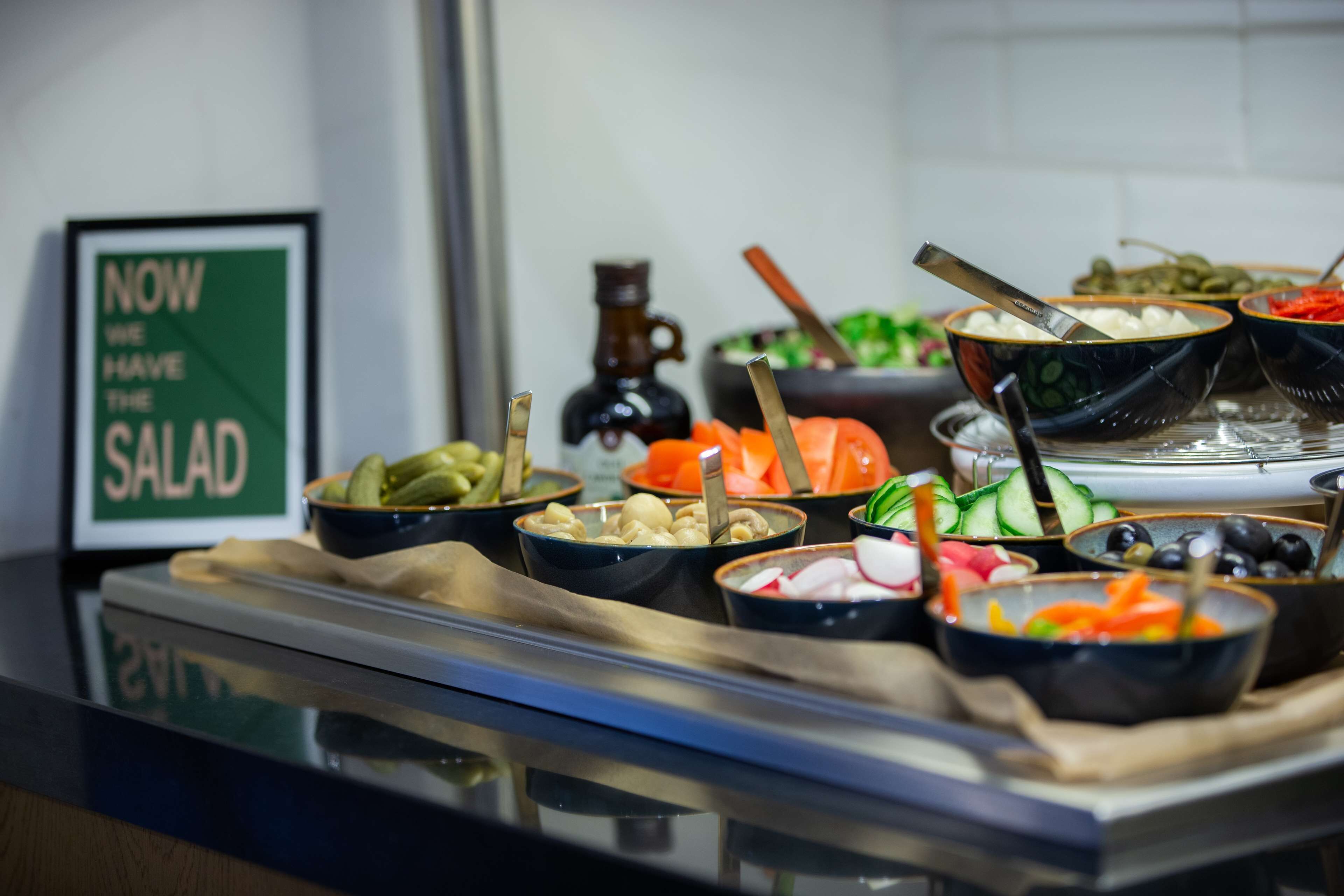 Un bufé con diversos platos, entre ellos ensaladas, verduras y mariscos.