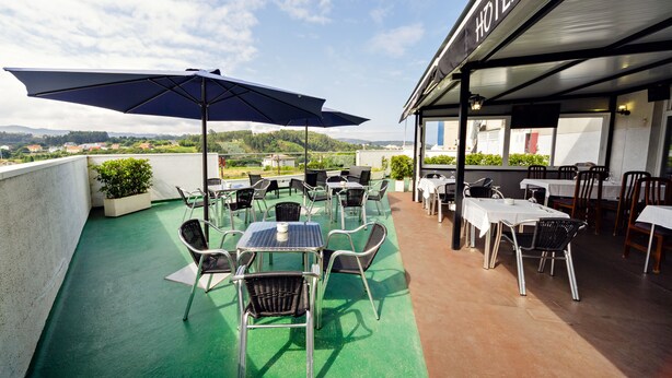 A rooftop terrace with outdoor seating, a view of the landscape, and a hotel sign. - Hotel As Camelias (Arteixo)