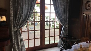 A room with a large window, a bed, a wooden dresser, and a small table with a lamp. - On-the-Summit Lodge & Conference Venue (East London)