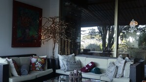 A cozy living area with a sofa, cushions, a glass coffee table, and a decorative branch with lights. - On-the-Summit Lodge & Conference Venue (East London)