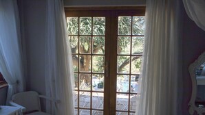 A room with a wooden door leading to an outdoor area with a pool and chairs. - On-the-Summit Lodge & Conference Venue (East London)