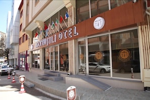 A hotel with a signboard displaying its name and multiple flags.