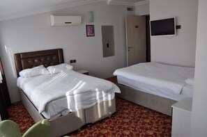 A hotel room with two beds, a television, an air conditioning unit, and a door.