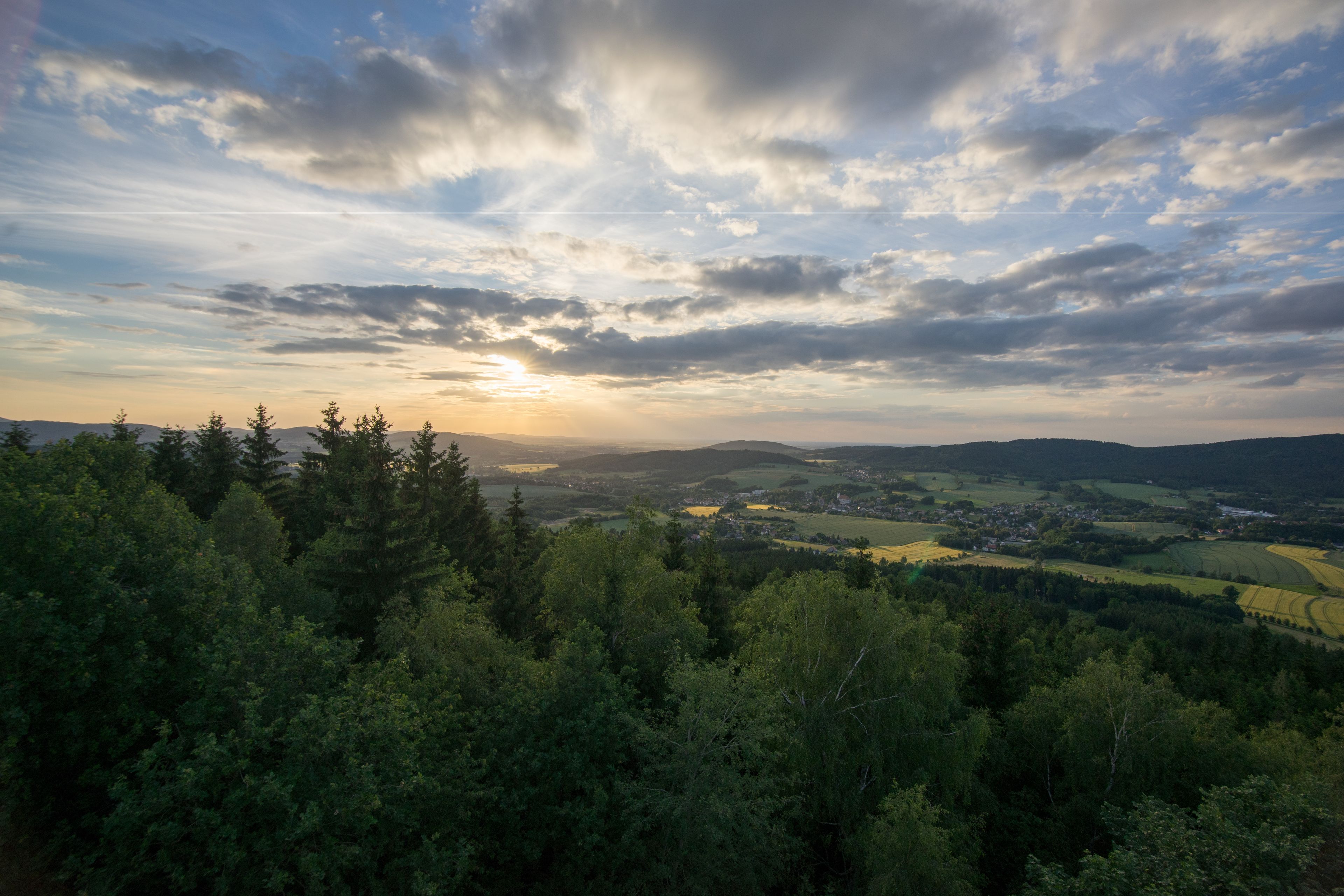Vista panorámica de un valle con un pueblo a lo lejos, rodeado de un bosque denso.