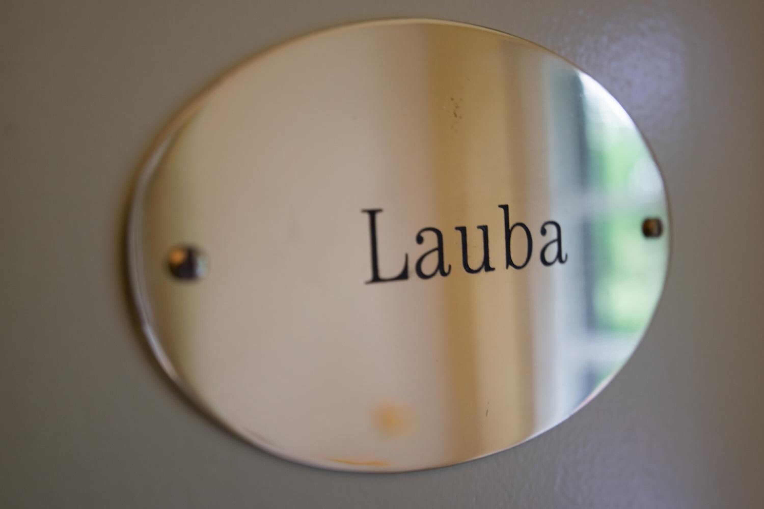A round, metallic sign with the name "Lauba" mounted on a wall.
