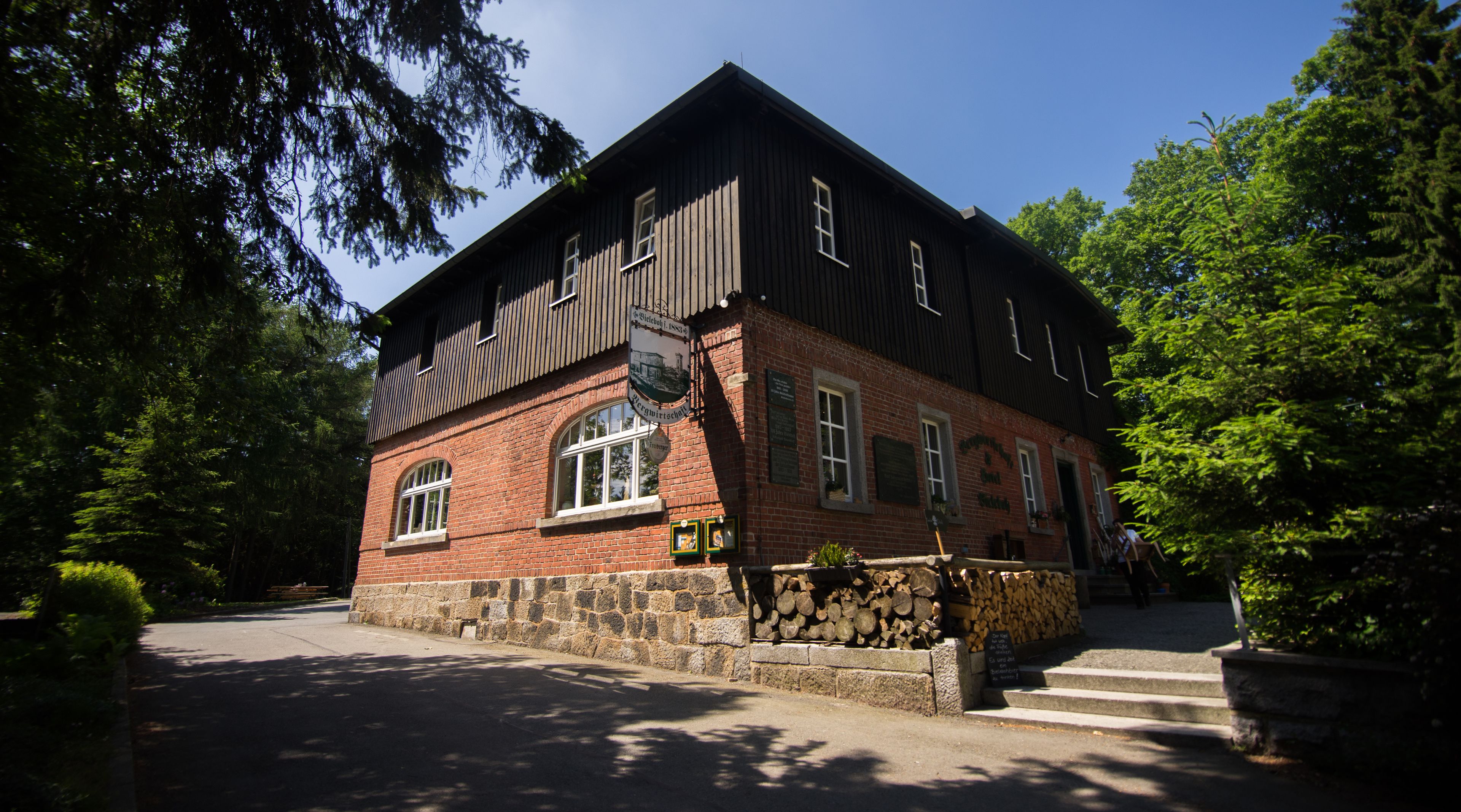 A two-story building with a brick facade and wooden upper levels, featuring arched windows and a stone foundation.