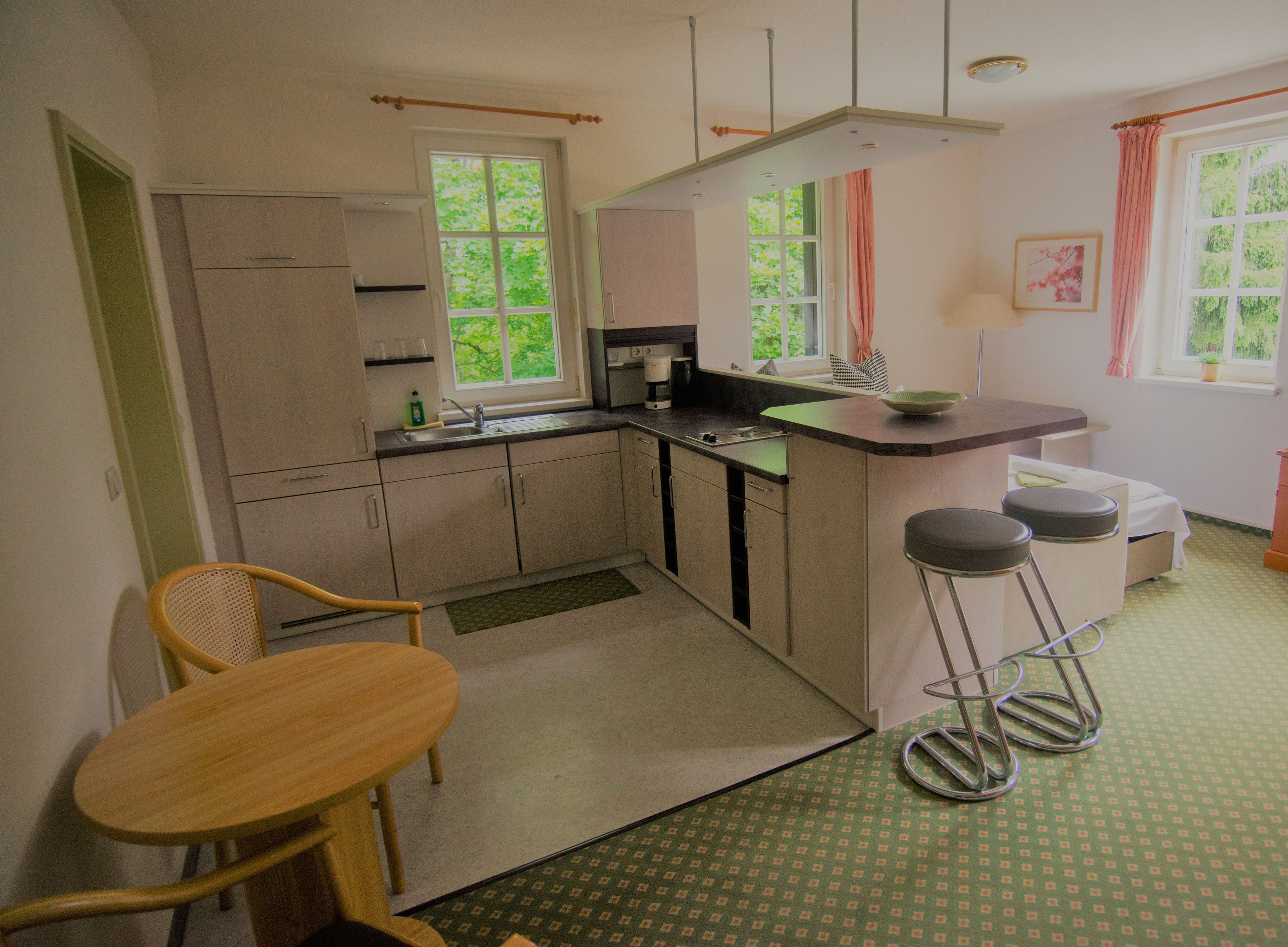 Cocina compacta con comedor, pileta y ventana con cortinas.