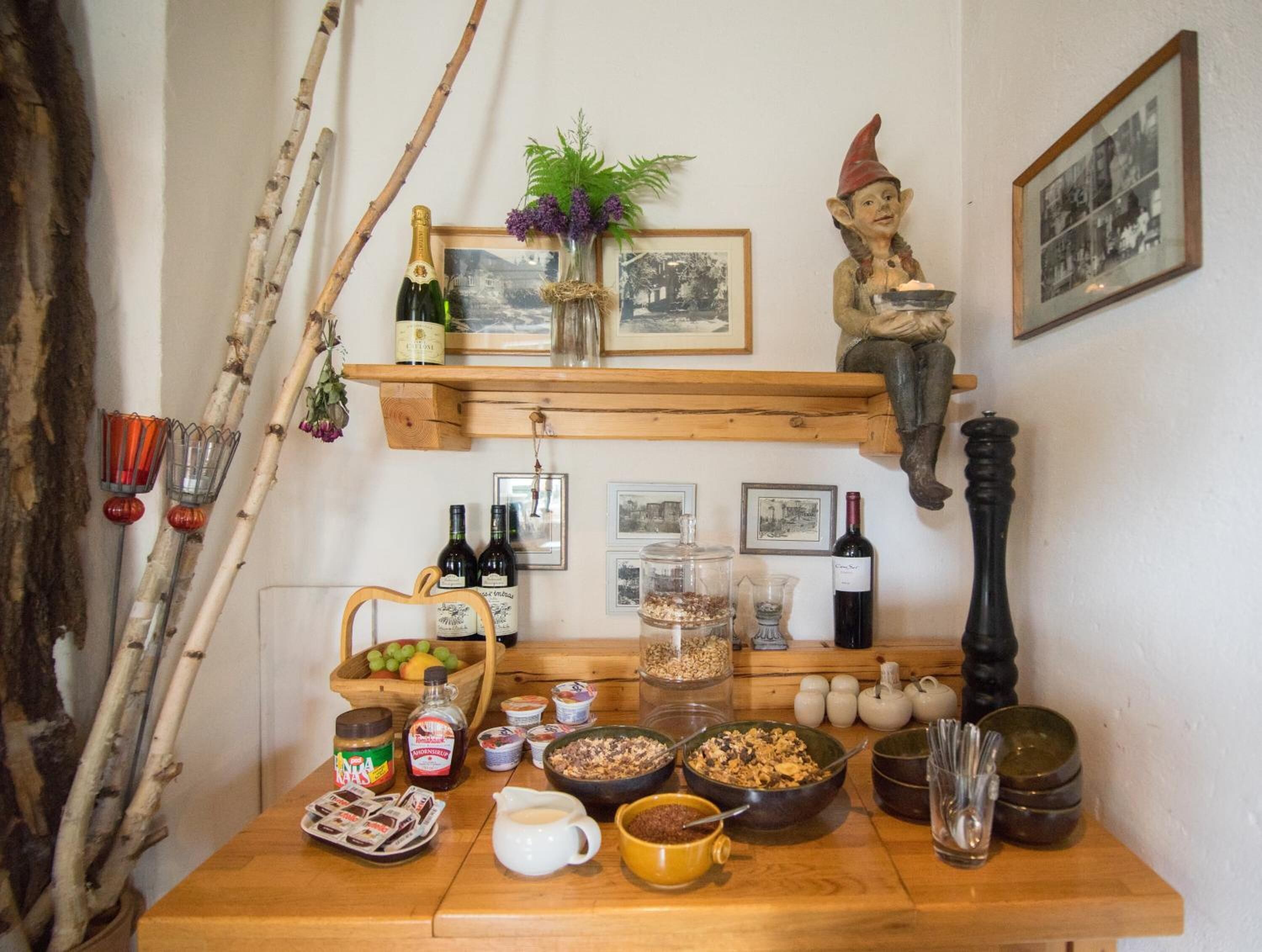 A wooden table with various food items, bottles, and a decorative figure.