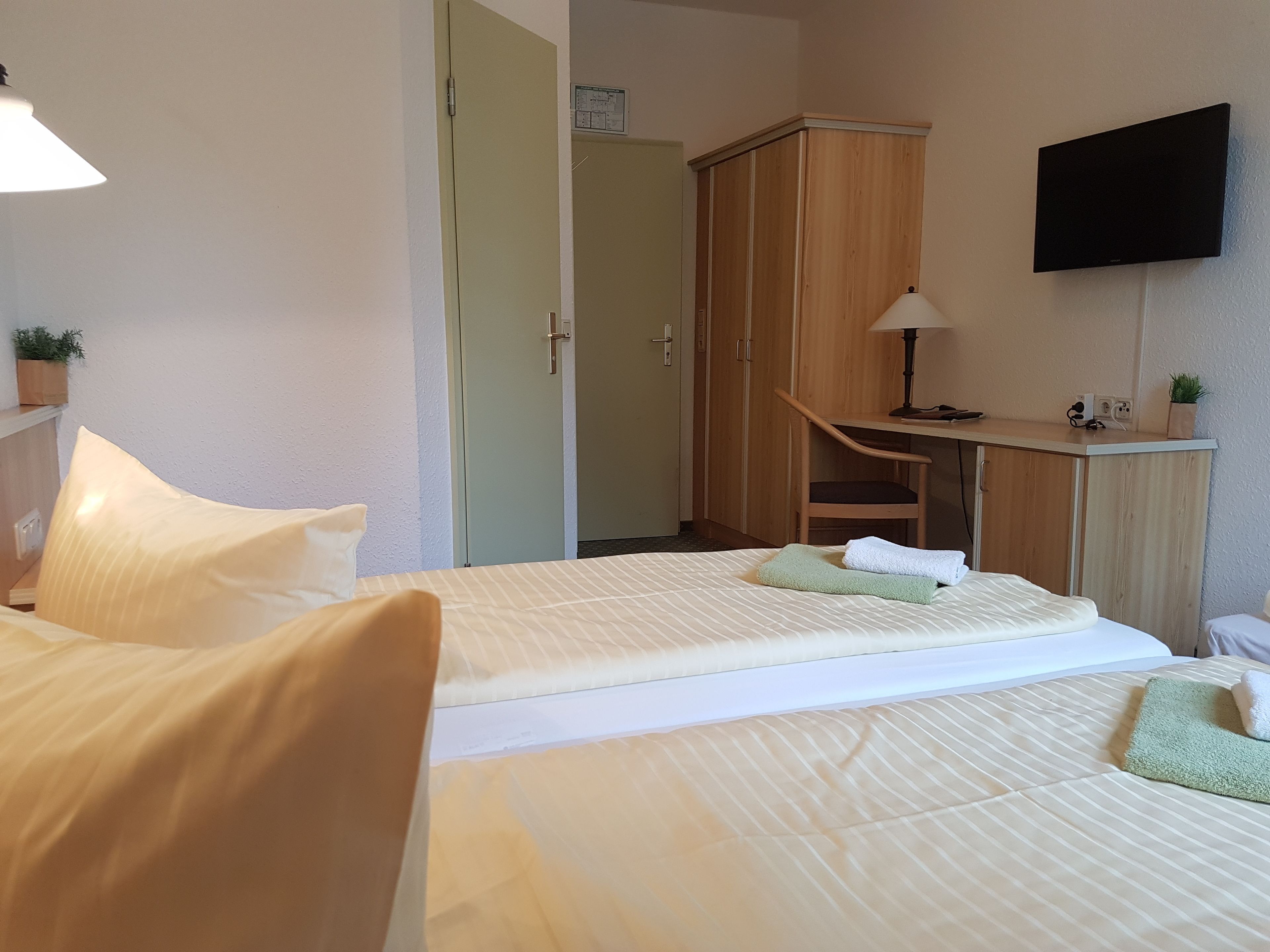 Habitación de hotel con dos camas, un escritorio, un televisor y un armario.