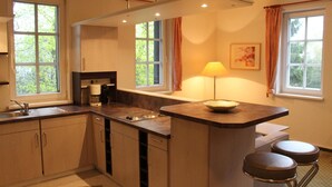 A compact kitchen with a central island, built-in cabinets, and a window with curtains.