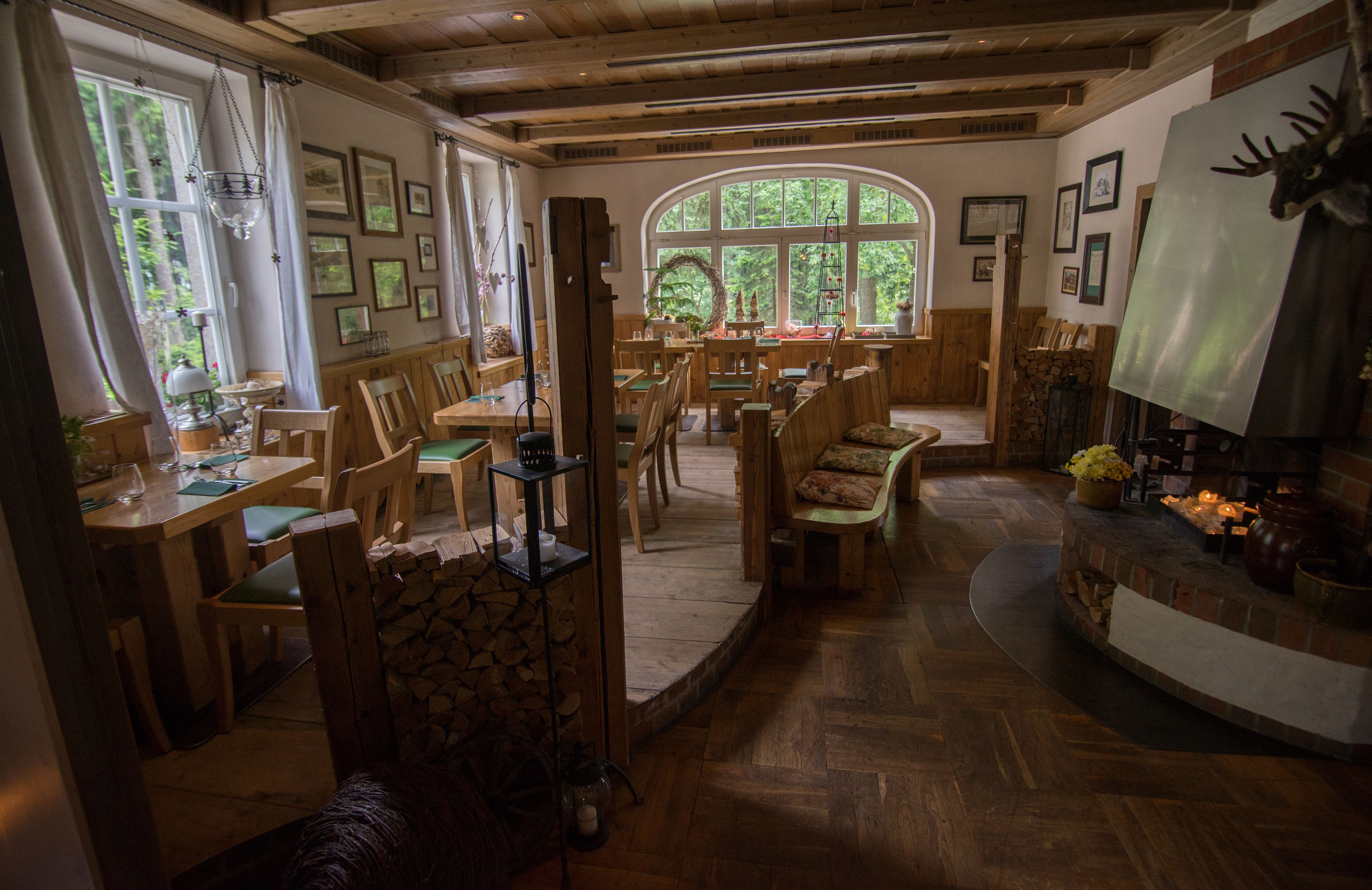 A cozy, rustic dining area with wooden furniture, a fireplace, and a large arched window providing natural light.