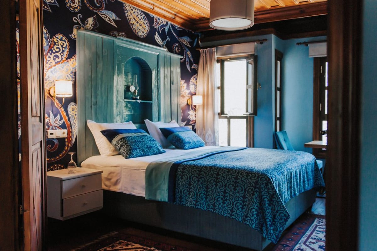 A bedroom with a bed, nightstands, a dresser, and a window.